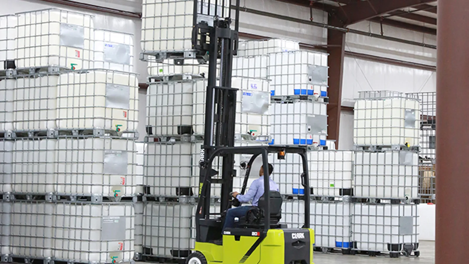 Clark electric forklift stacking IBC totes in a warehouse