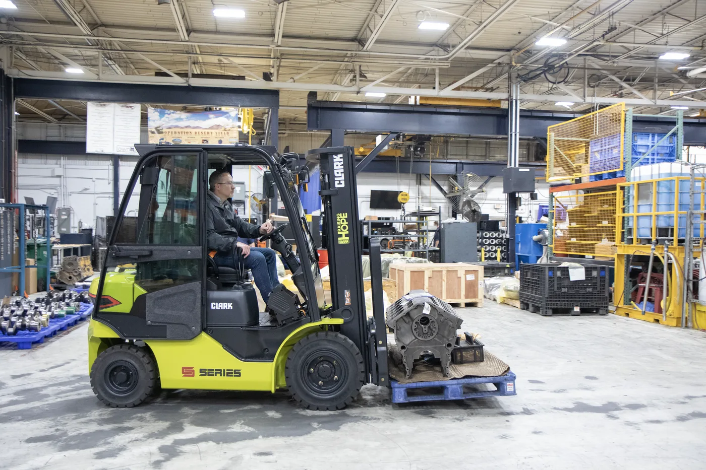 Clark forklift moving a load across a manufacturing plant floor